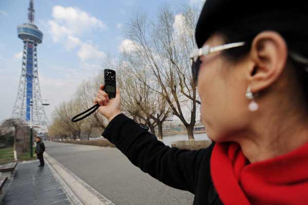 Jia Mingyou (R) measures wind speed before controlling an air vehicle to take aerial photos in Changchun, Northeast China's Jilin province, May 3, 2013. [Photo/Xinhua 