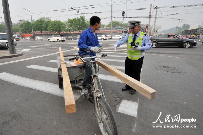 A tricyclist who rides on a motorway is fined 20 yuan ($3.20) at an intersection in Beijing, May 6, 2013. (Weng Qiyu /People’s Daily Online)