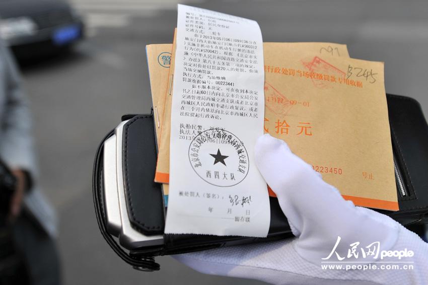 The policeman shows the ticket he issued to a jaywalker. (Weng Qiyu /People’s Daily Online)