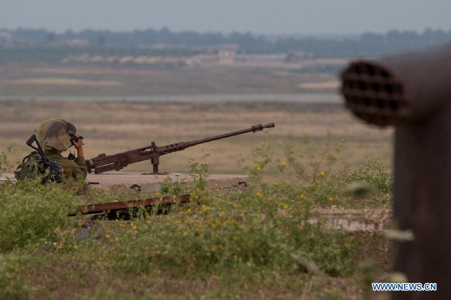 An Israeli soldier in an abandoned military outpost overlooks the ceasefire line between Israel and Syria on the Israeli-occupied Golan Heights May 6, 2013. Israel Defense Forces (IDF) reported that 2 stray mortars shot from Syria landed in Golan Heights on Monday.(Xinhua/Jini)