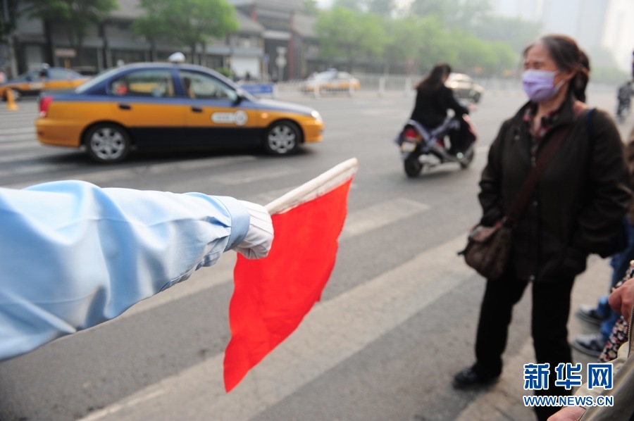 Pedestrians follow traffic warden’s direction at a crossing in Beijing, May 6, 2013. (Xinhua/Li Xin)