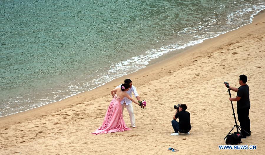 Photo taken on May 5, 2013 shows a couple pose for pictures on a beach in Ma Wan, an island in south China's Hong Kong. Ma Wan, which got the name from Mazu, the goddess of sailors, used to be a fishing village. Now the Ma Wan Park and Noah's Ark Museum here attract many tourists. (Xinhua/Li Peng)