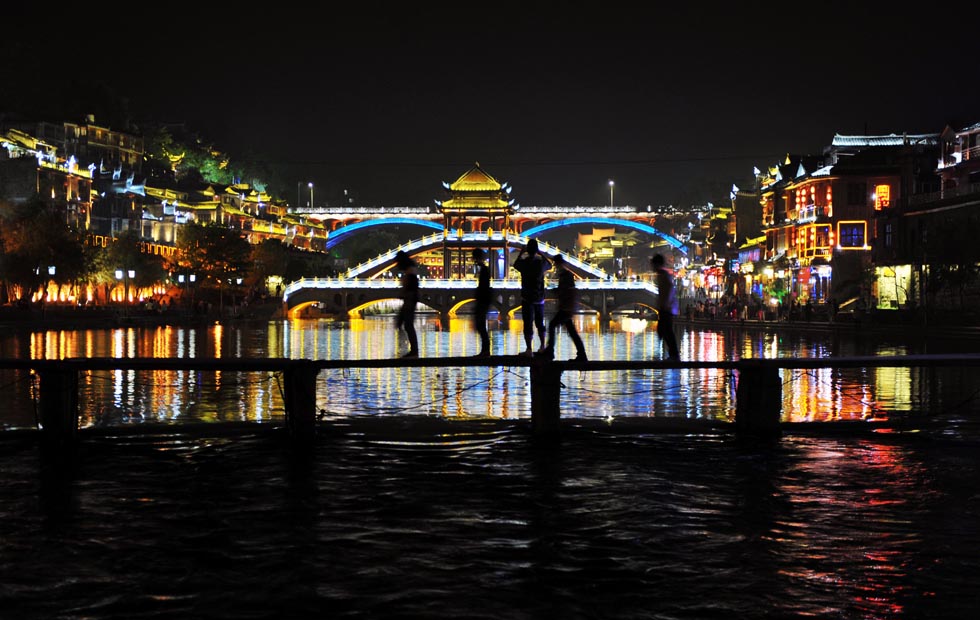 Visitors walk through a wooden bridge in Fenghuang Town on April 27, 2013. Since April 10, Fenghuang in Hunan began to charge 148 yuan (24 U.S. dollars) for tickets, causing disputes. (Xinhua Photo/ Zhang Zhongzhi)