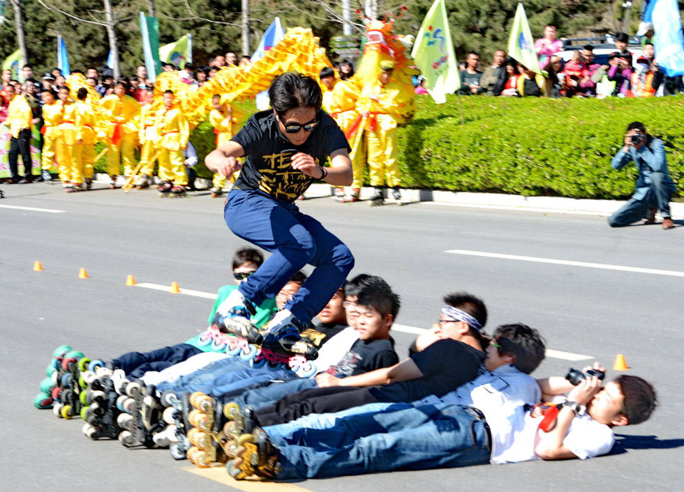 A skater performs skating stunts, leaping over the men lying on the ground in the Olympic Avenue Park in Hebei province. (Xinhua Photo/ Yang Shiyao)
