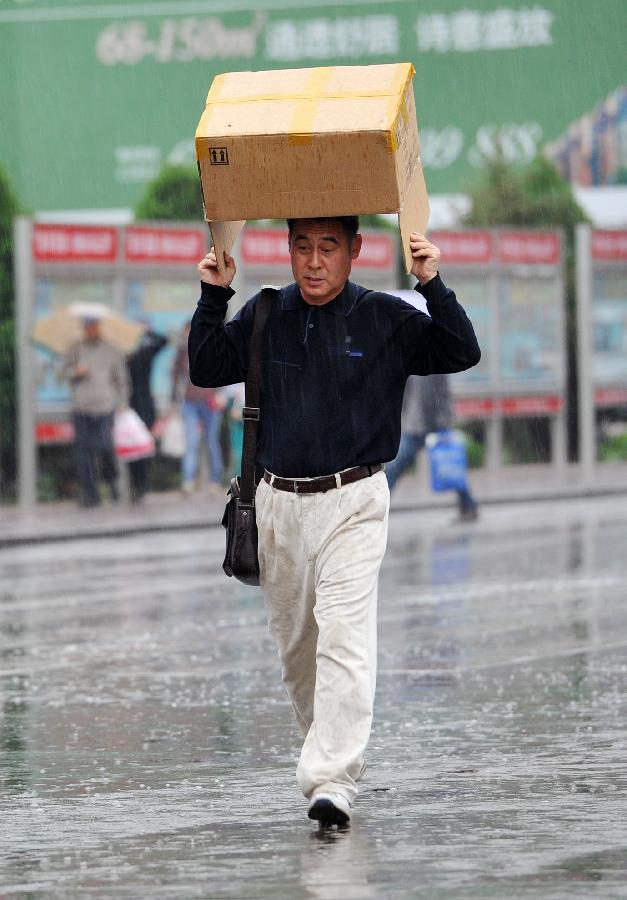 A man with a paper box overhead walks in rain in Yinchuan, capital of northwest China's Ningxia Hui Autonomous Region, May 7, 2013. The local meteorological observatory issued a yellow alert on thunderstorm on Tuseday as a thunderstorm hit Yinchuan the same day. (Xinhua/Peng Zhaozhi) 