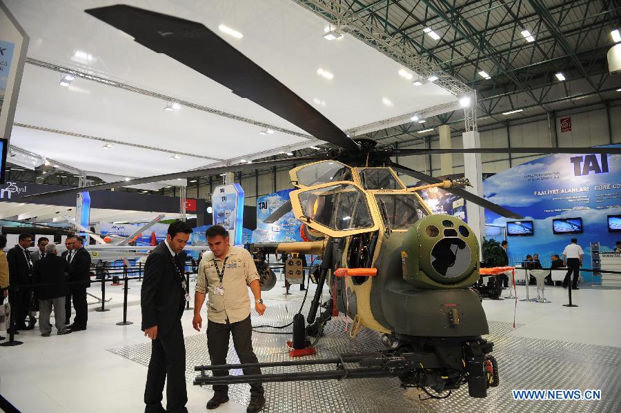 A guest asks the staff about the T129 multirole combat helicopter shown by TAI company of Turkey in Istanbul, Turkey, May 7, 2013. The 11th International Defence Industry Fair was opened on Tuesday, with 781 companies from 82 countries and regions attending the four-day fair. (Xinhua/Lu Zhe)