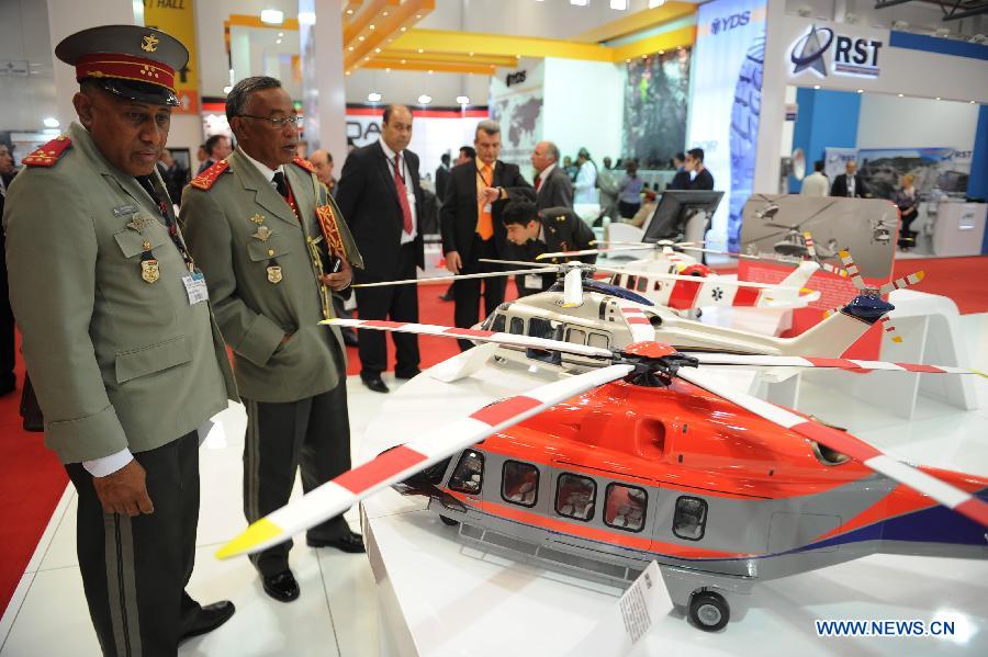 Military officers view helicopter models in front of a Turkey company booth in Istanbul, Turkey, May 7, 2013. The 11th International Defence Industry Fair was opened on Tuesday, with 781 companies from 82 countries and regions attending the four-day fair. (Xinhua/Lu Zhe)