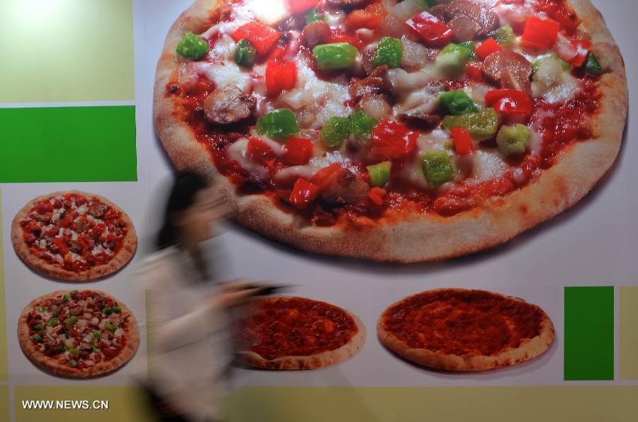A woman walks past a pizza poster at the 15th International Exhibition of Food & Drink, Hotel, Restaurant & Food Service Equipment, Supplies & Services (HOFEX) in south China's Hong Kong, May 7, 2013. The four-day HOFEX 2013 kicked off on Tuesday at Hong Kong Convention & Exhibition Center. (Xinhua/Chen Xiaowei)