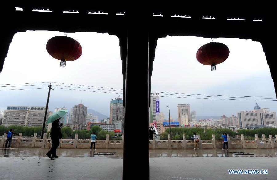 Citizens visit a park in rain in Lanzhou, capital of northwest China's Gansu Province, May 8, 2013. A rainfall hit the city from Tuesday night to Wednesday, helping to alleviate the lingering drought since winter. (Xinhua/Nie Jianjiang) 