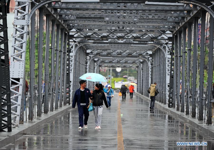 Citizens walk across a bridge in rain in Lanzhou, capital of northwest China's Gansu Province, May 8, 2013. A rainfall hit the city from Tuesday night to Wednesday, helping to alleviate the lingering drought since winter. (Xinhua/Nie Jianjiang)