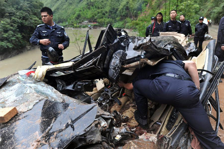 Policemen check a car destroyed by a landslide on S210 road from Lushan County to Baoxing County, southwest China's Sichuan Province, May 9, 2013. Three were killed among the nine people trapped by the landslide which took place Thursday near the epicenter of a 7.0-Magnitude earthquake that struck on April 20. (Xinhua/Hua Xiaofeng)