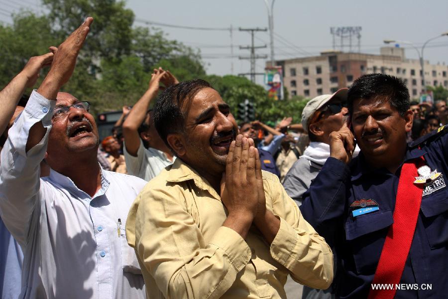 People react as they watch ongoing rescue operation at the fire site in eastern Pakistan's Lahore on May 9, 2013. One killed, dozens of people reportedly trapped as fire erupted at LDA Plaza in Lahore on Thursday, local media reported. (Xinhua/Jamil Ahmed)