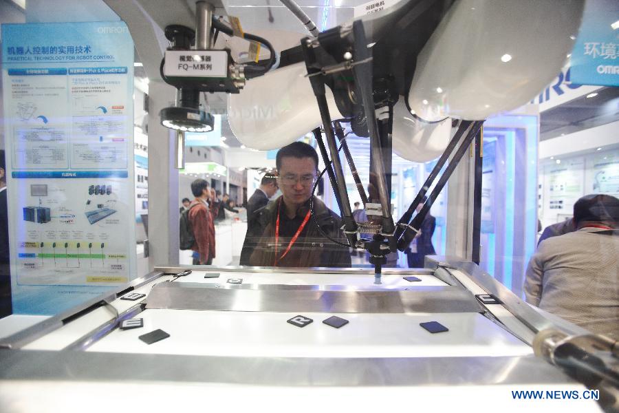 A visitor watches an automatic robot working during the China (Shanghai) International Technology Fair in Shanghai, east China, May 8, 2013. (Xinhua/Jin Xin)