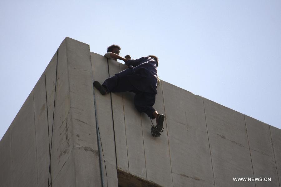 A man tries to save another on top of the LDA Plaza in Lahore, eastern Pakistan. Fire erupted on the seventh floor of the LDA Plaza in Lahore and quickly spread to higher floors, leaving many people trapped inside the building. At least three people fell from the high floors trying to avoid the fire that engulfed the building, local media reports. (Xinhua/Jamil Ahmed)