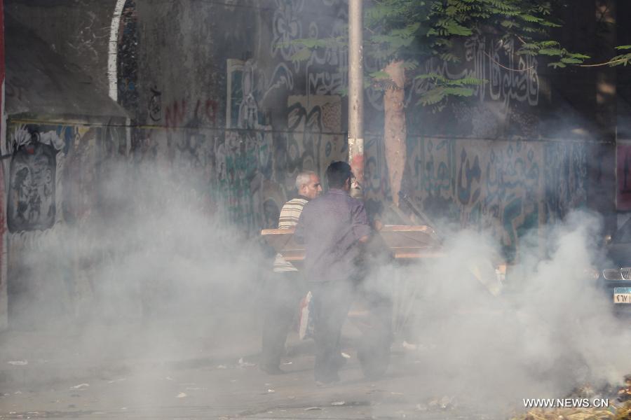 Egyptian citizens walk through teargas smoke fired by riot police after some protestors blocked Muhammad Mahmoud street which leads to the ministry of interior near Tahrir square after an Egyptian court sentenced some protestors accused of breaking into the presidential palace to 15 days awaiting investigations and final sentence, in Cairo, May 9, 2013. (Xinhua/Amru Salahuddien) 