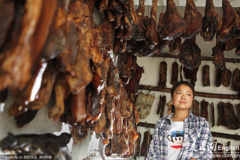 Jiang Dan, 23, is in her bacon shop in the new Beichuan county of Mianyang city of Sichuan on April 16, 2013. In the Wenchuan Earthquake, she was buried in the ruins and miraculously survived after being rescued. Now she has re-opened the bacon shop in Beichuan. (Photo/CFP)