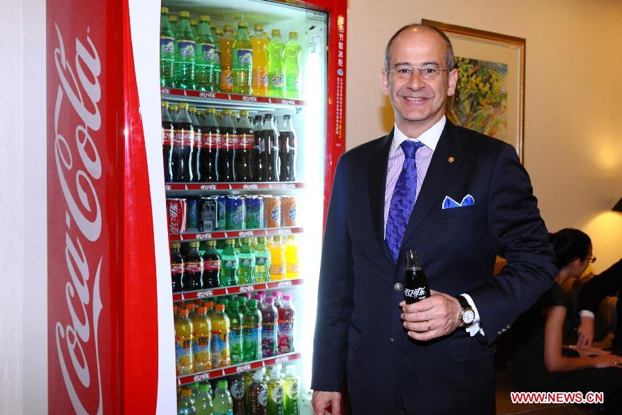 Ahmet Bozer, president of Coca-Cola International, poses beside a vending machine in Beijing, capital of China, May 9, 2013. The Coca-Cola Company announced here on Thursday that it will continue to increase investment levels in China. Bozer said during an interview that 4 billion U.S. dollars of investment will be added by 2014 in China. And he explained that the investment is mixed with marketing assets like plants, transportation and retail outlets. (Xinhua/Wu Kaixiang) 