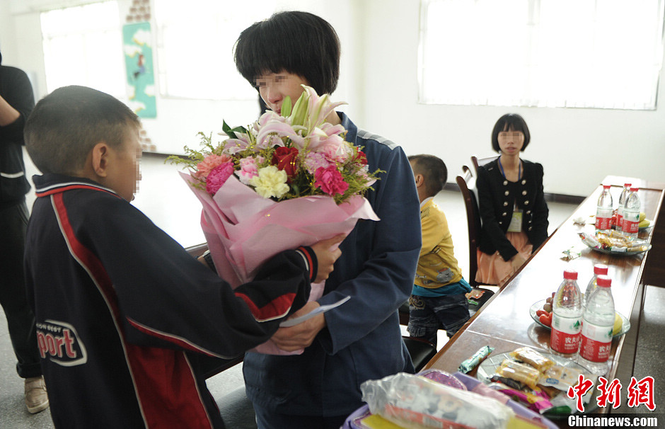 A child presents flowers to his mother in prison. Three children came to visit their mothers in Women's Prison in Chongqing before Mother's Day. (CNS/Chen Chao)