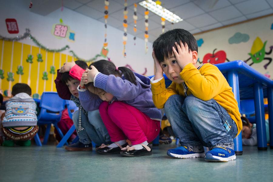 Children take part in an earthquake drill at a kindergarten in Hefei, capital of east China's Anhui Province, May 10, 2013, two day ahead of the Disaster Prevention and Reduction Day. The Disaster Prevention and Reduction Day was set in 2009, after a devastating earthquake hit Sichuan and neighboring Gansu and Shaanxi provinces on May 12, 2008, leaving 87,000 people dead or missing. (Xinhua/Du Yu) 