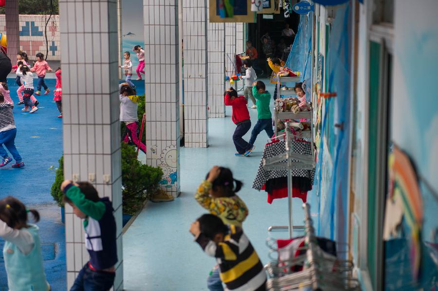 Children take part in an earthquake drill at a kindergarten in Hefei, capital of east China's Anhui Province, May 10, 2013, two day ahead of the Disaster Prevention and Reduction Day. The Disaster Prevention and Reduction Day was set in 2009, after a devastating earthquake hit Sichuan and neighboring Gansu and Shaanxi provinces on May 12, 2008, leaving 87,000 people dead or missing. (Xinhua/Du Yu)