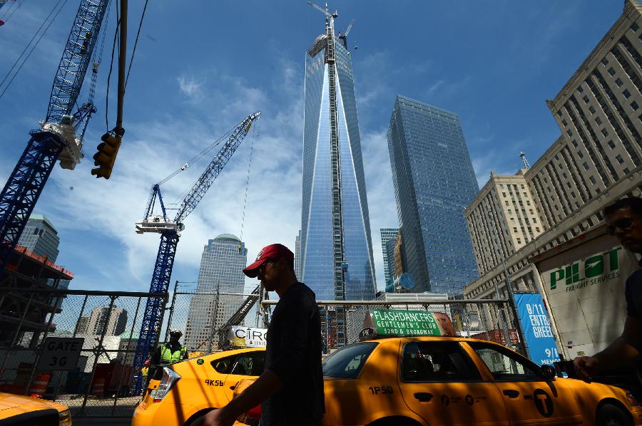A visitor walks by One World Trade Center (WTC) in New York, May 10, 2013. Workers have installed the final sections of the silver spire atop WTC on Friday, which brings the iconic New York City structure to its full, symbolic height of 1,776 feet (541 meters). (Xinhua/Wang Lei) 