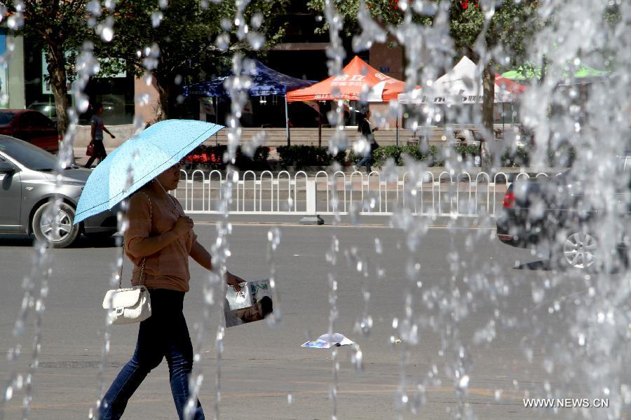 A woman holding an umbrella walks on the street in Baoding City, north China's Hebei Province, May 11, 2013. A hot wave hit Hebei these days, with the highest temperature in parts of the province reaching 37 degrees Celsius. (Xinhua/Zhu Xudong)  