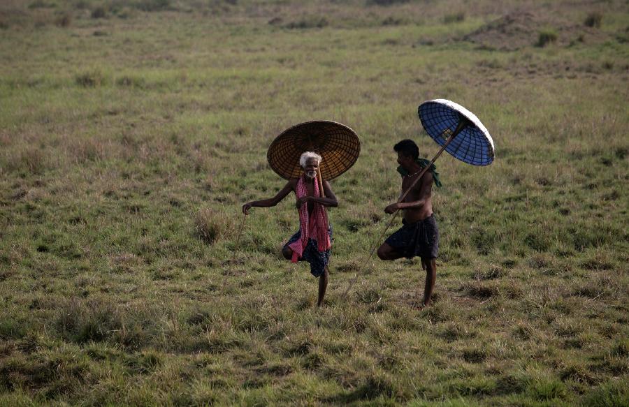 Holding traditional handmade umbrellas, two villagers have a rest in the suburb of Bhubaneswar, the capital of Orissa State in India, May 11, 2013. (Xinhua Photo)