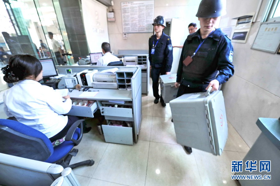 Armed security guards escort cash boxes to the bank.  (Xinhua Photo)