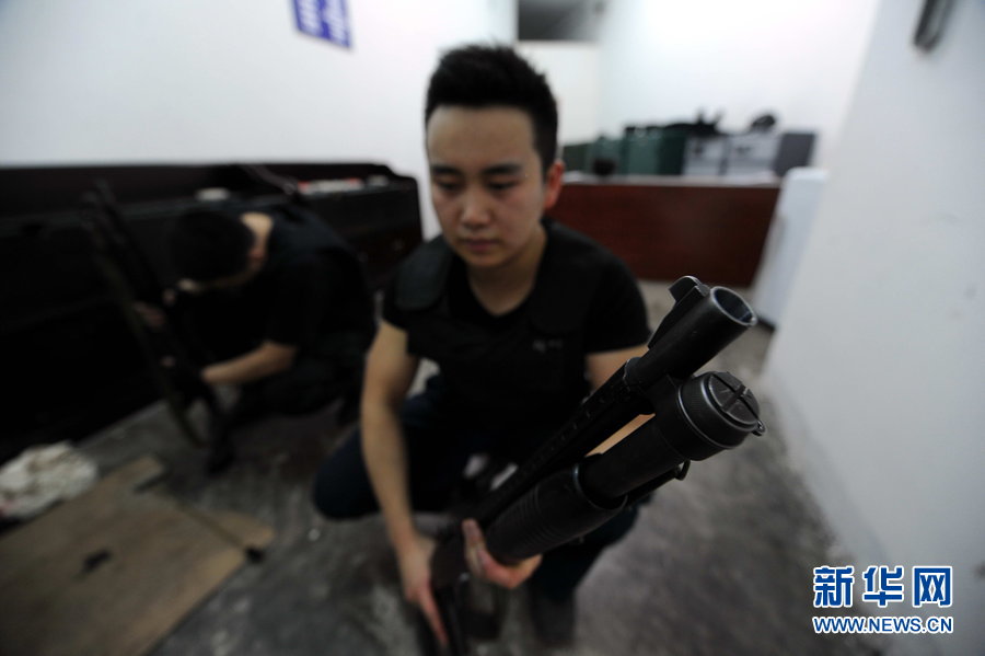 Armed cash transit security guards clean guns before starting an escort mission. (Xinhua Photo)