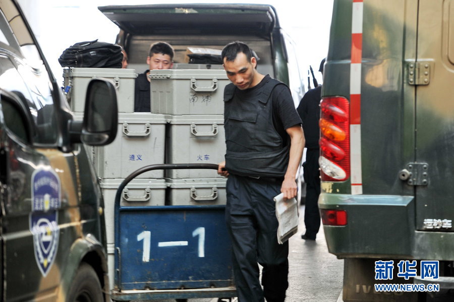 Armed security guards carry boxes of cash out of vault and put them on the armored van. (Xinhua Photo)
