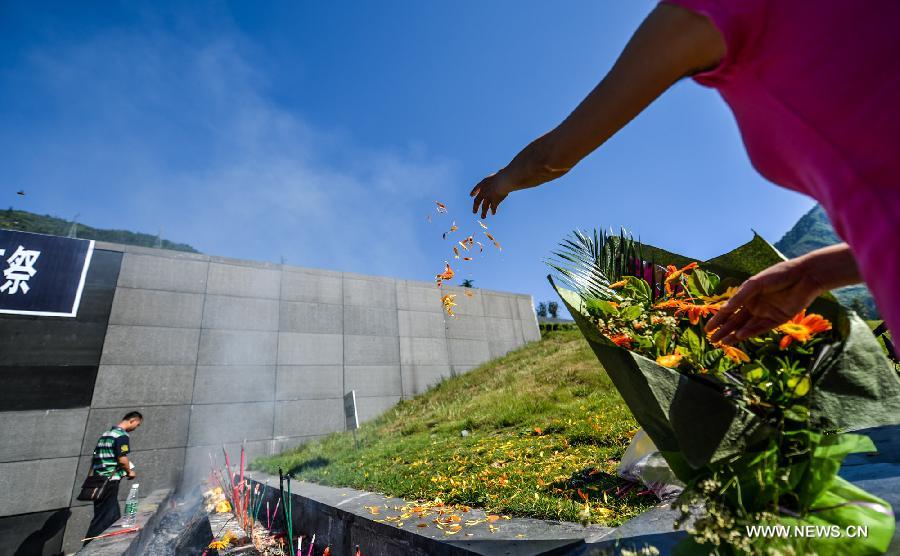 A woman scatters flower petals to mourn for victims who died in a massive earthquake five years ago in Yingxiu Township of Wenchuan County, southwest China's Sichuan Province, May 12, 2013. The devastating 8.0-magnitude earthquake on May 12, 2008 left more than 80,000 people dead or missing. (Xinhua/Bai Yu)