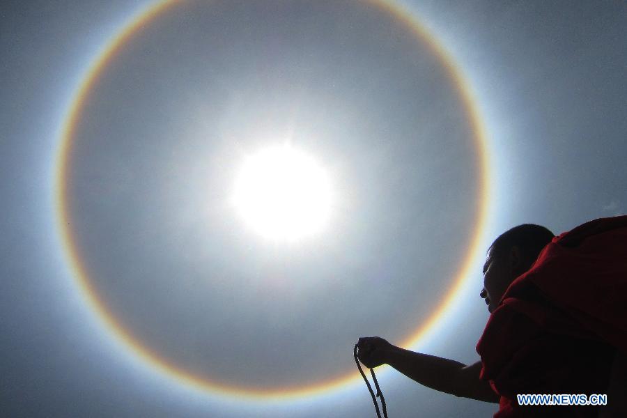 A monk looks at a solar halo occurring in Qamdo, southwest China's Tibet Autonomous Region, May 12, 2013. (Xinhua/Wen Tao) 
