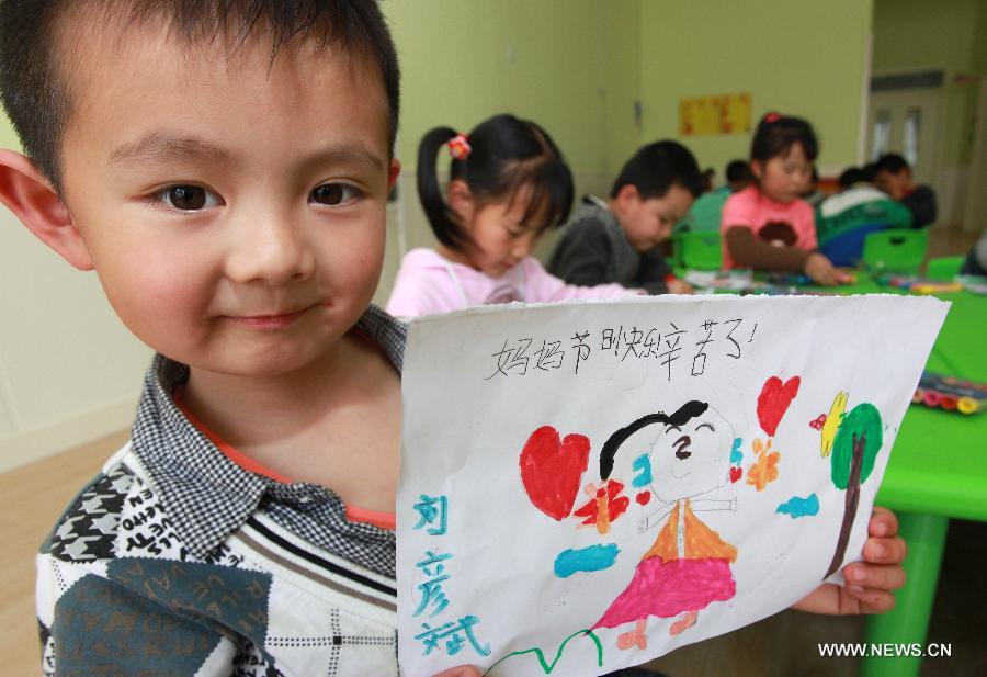 A little boy displays his drawing of his mother during a celebration of the Mother's Day in Jimo, east China's Shandong Province, May 12, 2013. (Xinhua/Liang Xiaopeng)