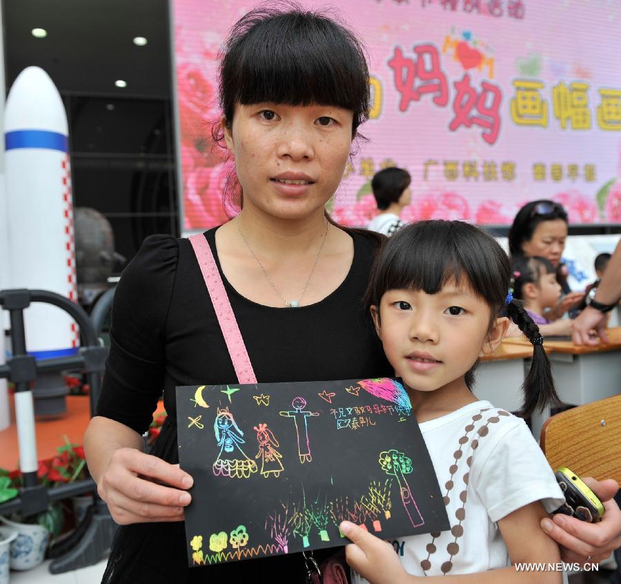 A little girl presents her drawing of her mother during a celebration of the Mother's Day in Nanning, capital of south China's Guangxi Zhuang Autonomous Region, May 12, 2013. (Xinhua/Yu Xiangquan) 