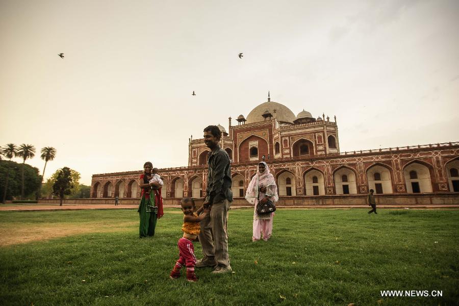 Tourists play on the lawn of Humayun's Tomb in New Delhi, capital of India, May 12, 2013. Humayun's Tomb, located in east New Delhi, was built in 1569 to 1570 by Humayun's widow. As a precursor to the Taj Mahal, it stands on a platform of 12,000 square meters and reaches a height of 47 meters. The earliest example of the Persian influence in Indian architecture, the tomb itself is in the center of a large garden, surrounded by 12 hectares of gardens with pools joined by channels. The tomb brought Persian style to Delhi, but the two-tone combination of red sandstone and white marble is local, which shows the merging of different cultures. Humayun's Tomb was inscribed on the World Heritage List by the United Nations Educational, Scientific and Cultural Organization in 1993. (Xinhua/Zheng Huansong)