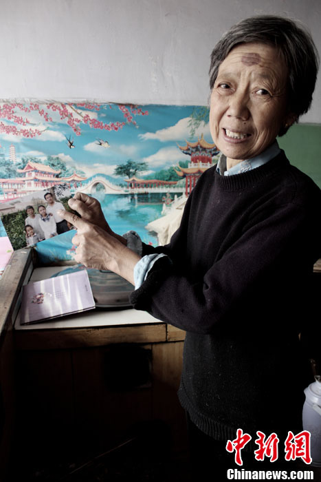 Wu Hanlian often looks at the photos of her children who are her pride and joy. Wu was born in an intellectual family and loves reading. However, she had to leave school to take care of her sick father then. (Photo by Zhou Panpan/ Chinanews.com)