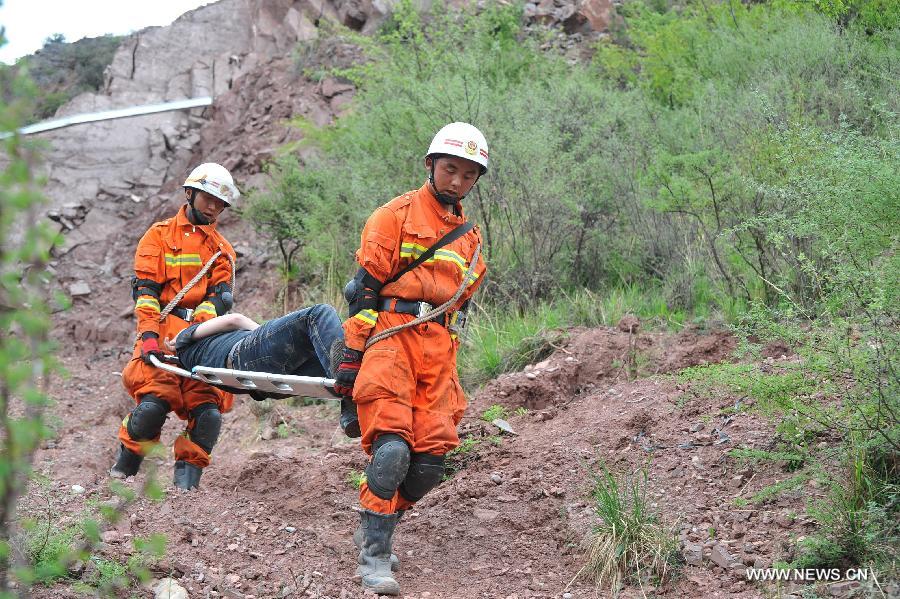 Fire fighters carry "an injured person" during an earthquake drill in Qamdo, southwest China's Tibet Autonomous Region, May 13, 2013. The drill was held by local fire fighting department to test and evaluate their response and rescue ability in the event of disasters. (Xinhua/Wen Tao)