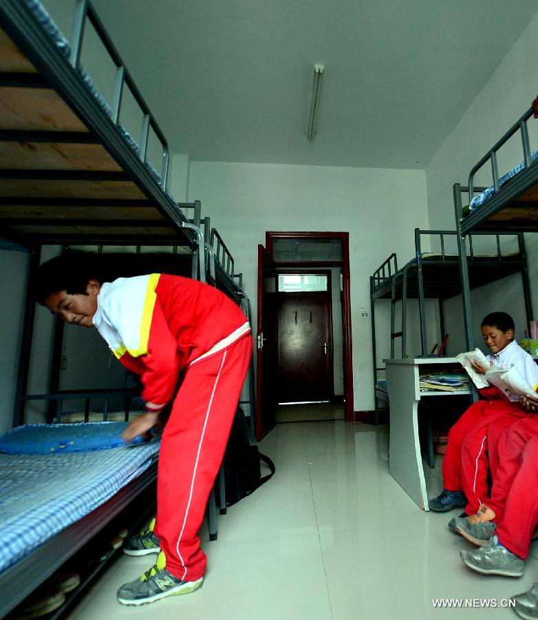 Orphan student Gama Dingjiang (L) makes his bed at the Bayi Orphan School in Yushu Tibet Autonomous Prefecture in northwest China's Qinghai Province, May 13, 2013. The school is now a home of 323 orphan students who are instructed and cared by 57 teachers. (Xinhua/Wang Bo)
