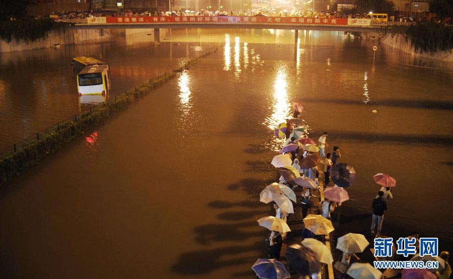 A bus and passengers are stranded under the Lotus Bridge by a sudden downpour in Beijing on July 21, 2012. The rain disrupted traffic in many areas of the city. (Photo/Xinhua)