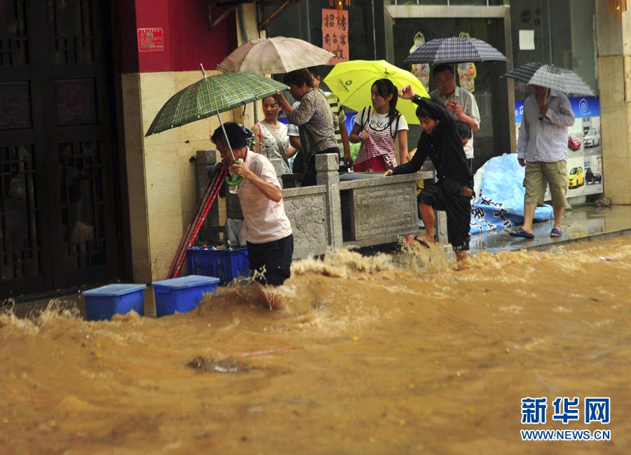 Pedestrians wade across a flooded street on April, 26, 2013. Persistent rain triggered flood in Sanya, south China's Hainan province. Red alert of rainstorm and thunder had been issued by Sanya Meteorological Station. (Photo/Xinhua)