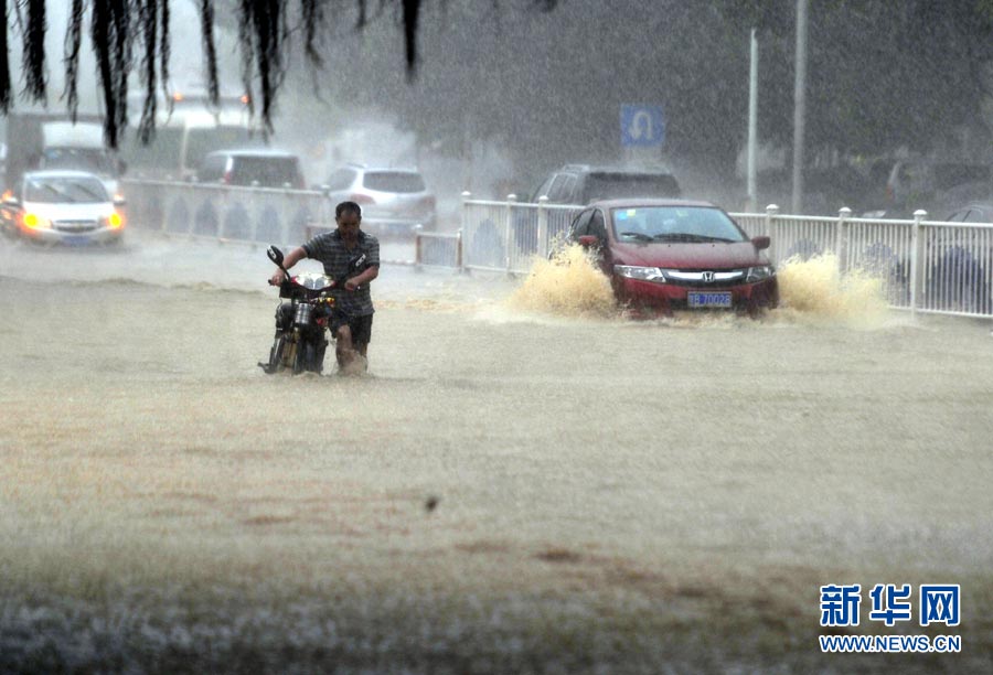 Pedestrians and vehicles wade in flooded street in South China’s Sanya city on April 26, 2013. A heavy rain hit the city, destroying roads and interrupting traffic. Sanya Meteorological Station announced a red alert. (Photo/Xinhua)
