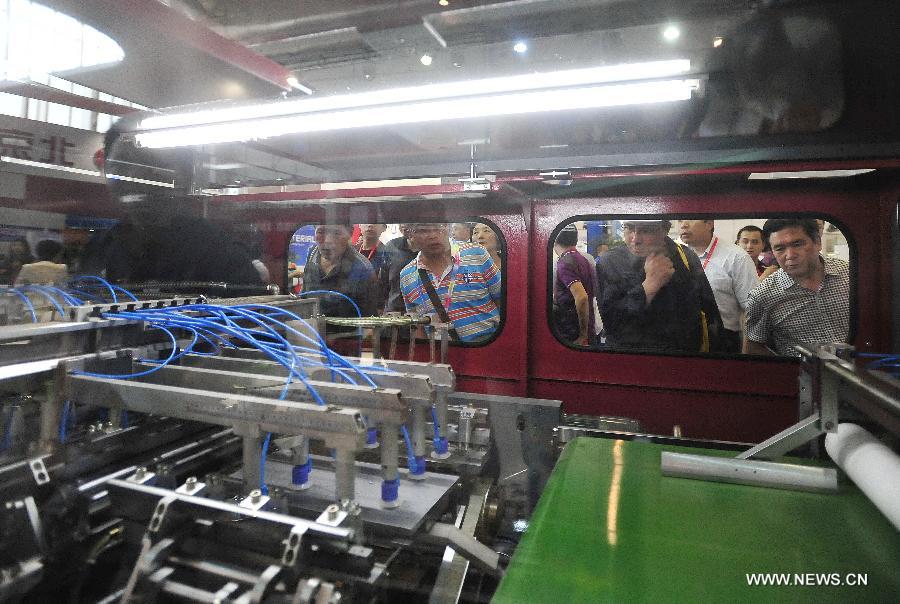 Visitors watch an automatic book covering making machine during the 8th Beijing International Printing Technology Exhibition in Beijing, capital of China, May 14, 2013. The five-day exhibition opened at New China International Center in Beijing Tuesday. (Xinhua/Xiao Xiao) 