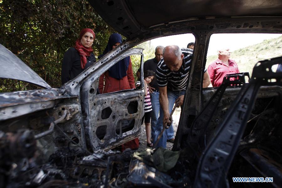 People inspect burnt vehicles that were set on fire by unknown vandals in the northern Arab-Israeli town of Umm al-Qutuf, south of Haifa, Israel, on May 14, 2013. (Xinhua/Muammar Awad)