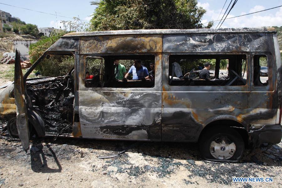 People inspect burnt vehicles that were set on fire by unknown vandals in the northern Arab-Israeli town of Umm al-Qutuf, south of Haifa, Israel, on May 14, 2013. (Xinhua/Muammar Awad)