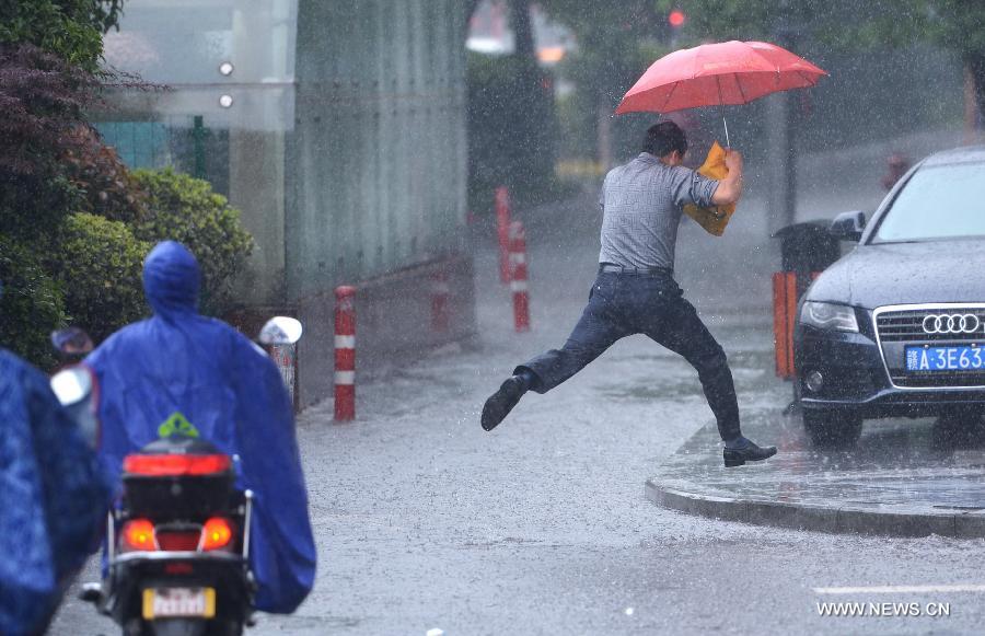 A citizen leaps over a waterlogged road in Nanchang, capital of east China's Jiangxi Province, May 15, 2013. A heavy rainfall hit Nanchang overnight. (Xinhua/Zhou Mi) 