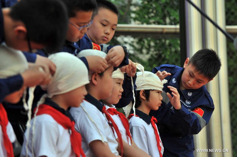 Pupils dress "wounds" during an earthquake drill at the Fendou Elementary School in Beijing, capital of China, May 15, 2013. (Xinhua/Li Wen) 