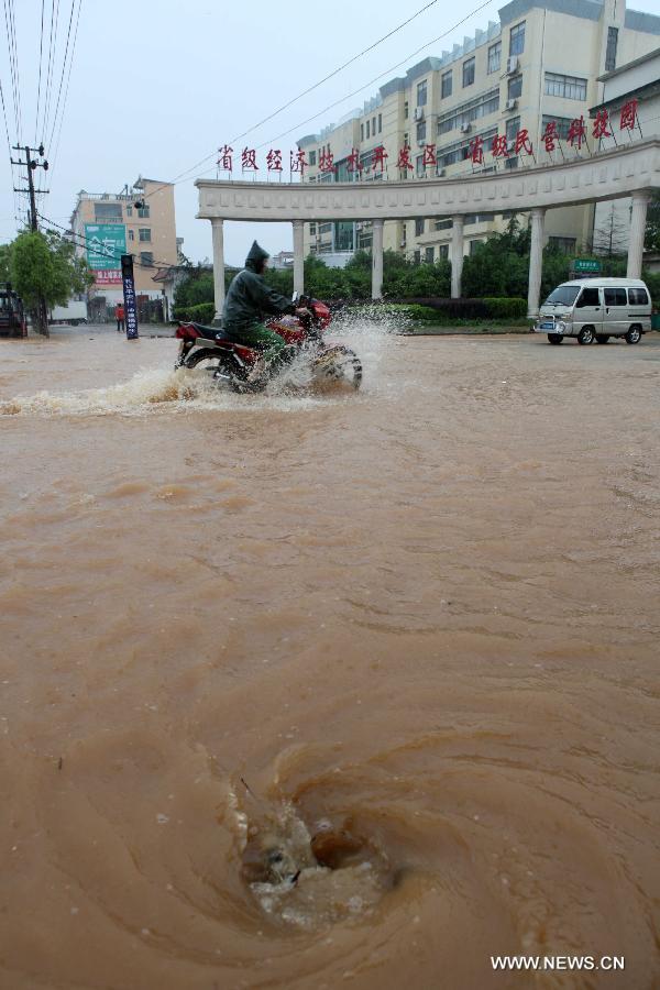 A man rides on the waterlogged road in Duchang County of Jiujiang City, east China's Jiangxi Province, May 15, 2013. A heavy rainfall hit the city on Wednesday. (Xinhua/Fu Jianbin)
