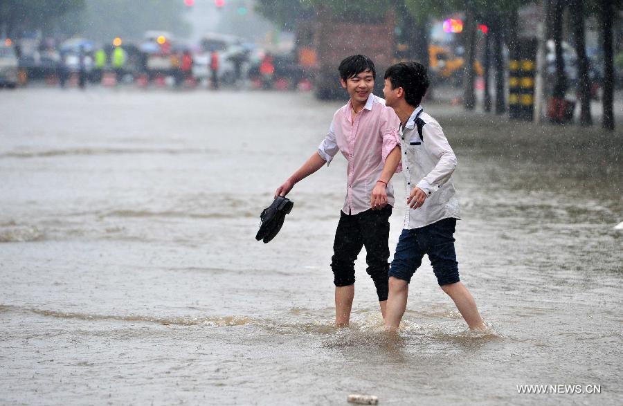 Citizens walk on a waterlogged road in Jiujiang City, east China's Jiangxi Province, May 15, 2013. A heavy rainfall hit the city on Wednesday. (Xinhua/Hu Guolin)