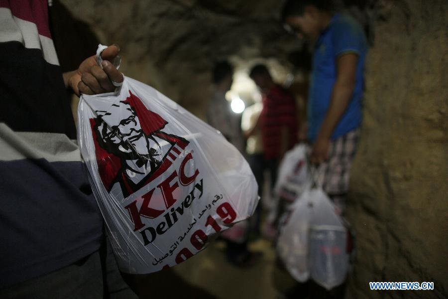 People deliver KFC food in the underground tunnel beneath the Gaza-Egypt border in the southern Gaza Strip city of Rafah on May 15, 2013. Ordering fast food from one of the world's most popular restaurants KFC has become possible in Gaza after Al-Yamama delivery company started to bring the food from the Egyptian north Sinai, which borders Gaza. (Xinhua/Wissam Nassar) 