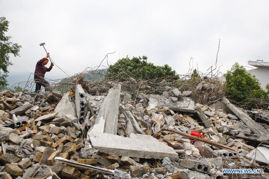 A woman smashes cement relics to get steel bars for reconstruction at Hongxing Village of Longmen Township in Lushan County, southwest China's Sichuan Province, May 15, 2013. People in Lushan County are trying to reconstruct their homes and start a new life after the 7.0-magnitude earthquake hit the county on April 20. (Xinhua/Cui Xinyu)